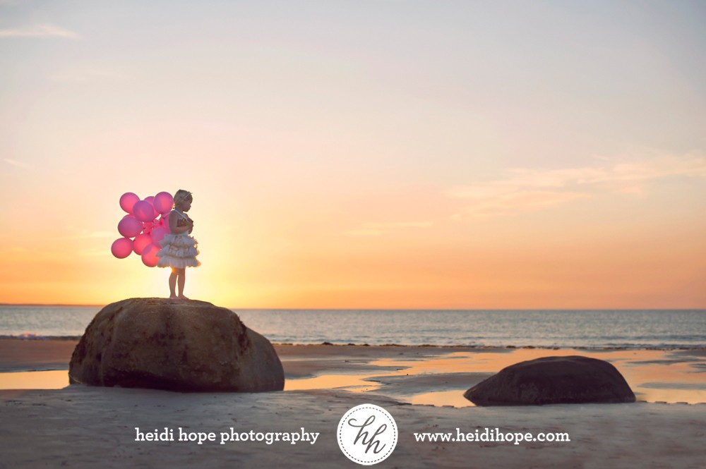 birthday girl holding balloons at the beach at sunrise by #heidihopephotography
